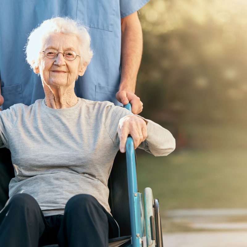 Healthcare, portrait and old woman in wheelchair with nurse in nature for wellness. Outdoors, disability and retired female with medical worker for healthy sunshine or enjoying time at park or garden